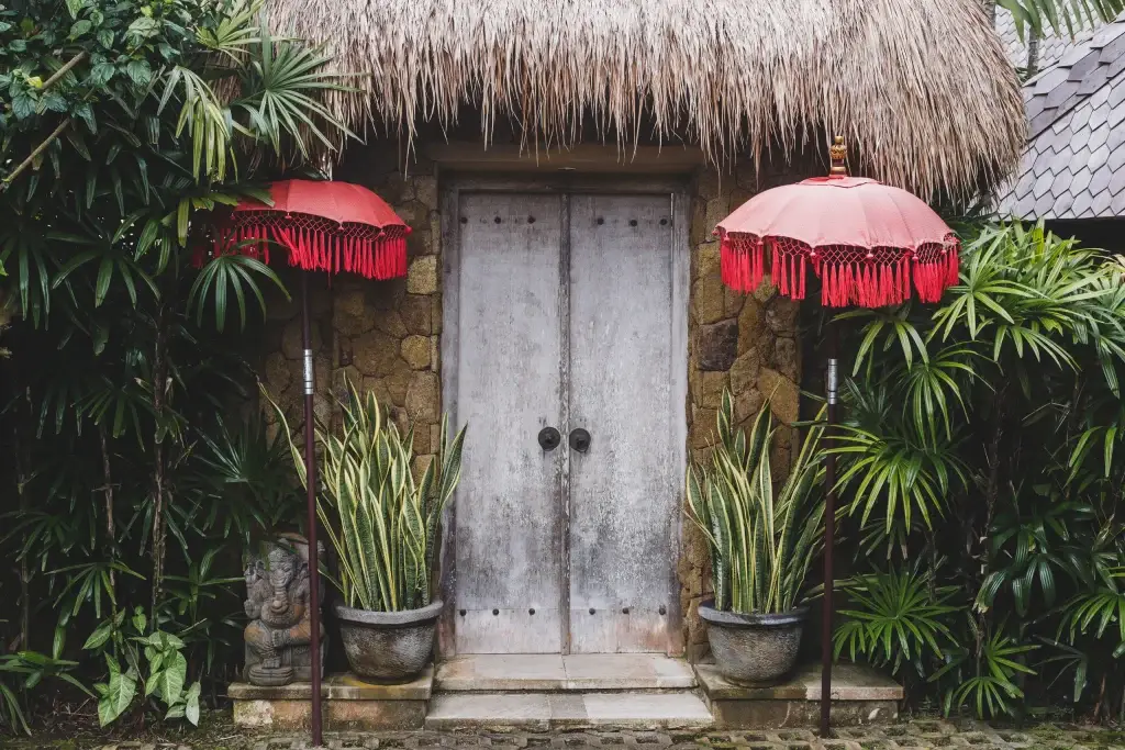 Kuta bali ornate door surrounded by red umbrellas and foliag
